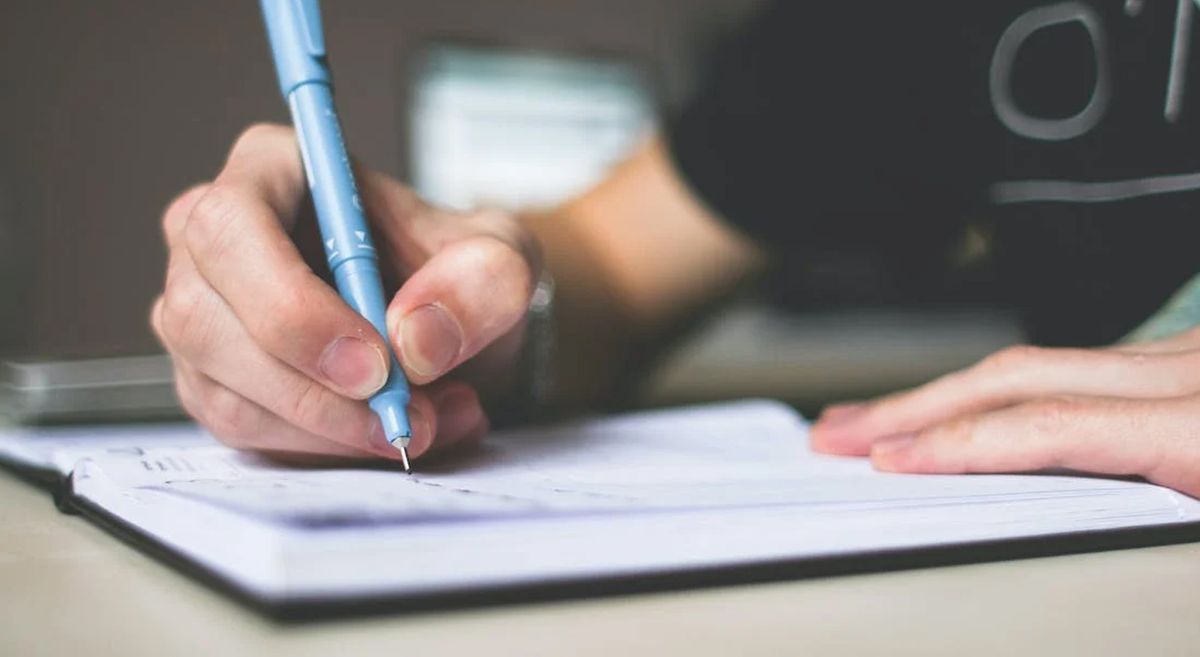 Picture of a person writing in a book